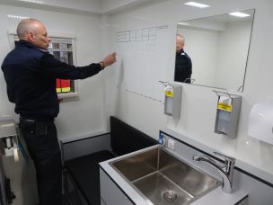 Thomas Marbes dokumentiert die Aussonderung der Schutzkleidung auf dem Whiteboard im Umkleideraum des GW PSA / Hygiene. (Bild: Christian Heinz / HFUK Nord)