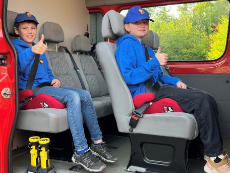 Kinderfeuerwehrangehörige sitzen auf Sitzerhöhungen im Feuerwehrfahrzeug.