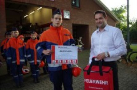 Foto oben © H.-G. Borchers:  Übergabe des Gutscheines, des Pokals und der Kühltasche an Dominic Schröder von der Jugendfeuerwehr Oering durch Christian Heinz von der HFUK Nord. 